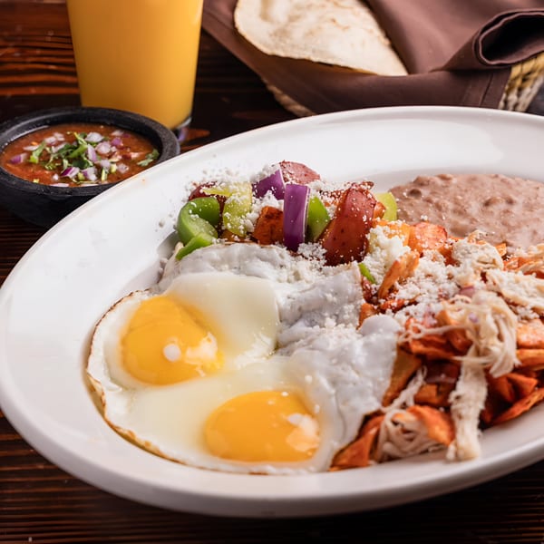El Tarasco's Mexican breakfast with two fried eggs, chilaquiles, refried beans, salsa, and orange juice.