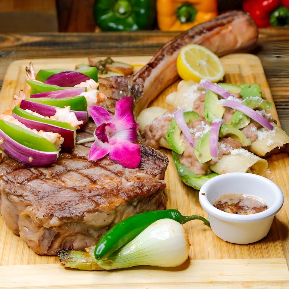 El Tarasco's Mexican steak and shrimp dish with enchiladas, avocado, onions, and a lemon slice.
